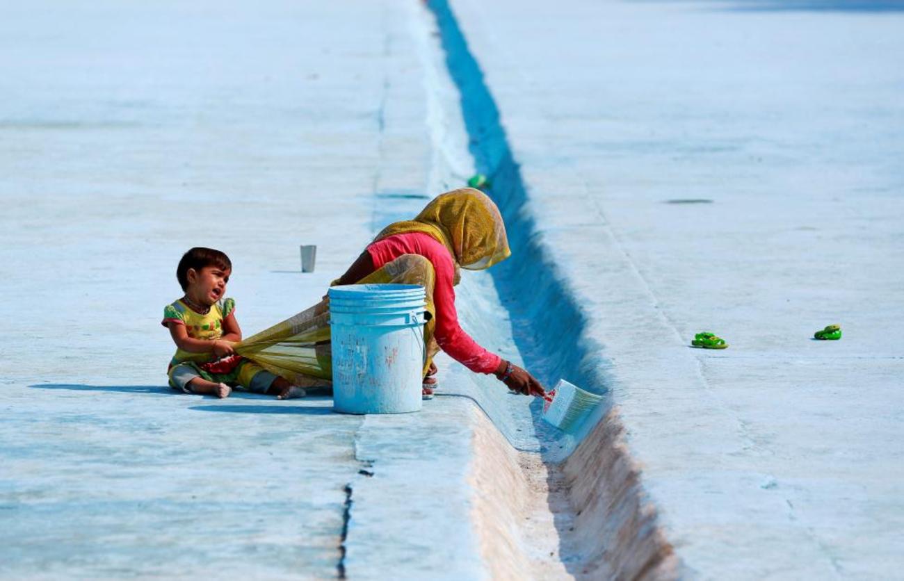 یک زن هندی در حال رنگ کردن کف یک استخر مصنوعی در دهلی نو